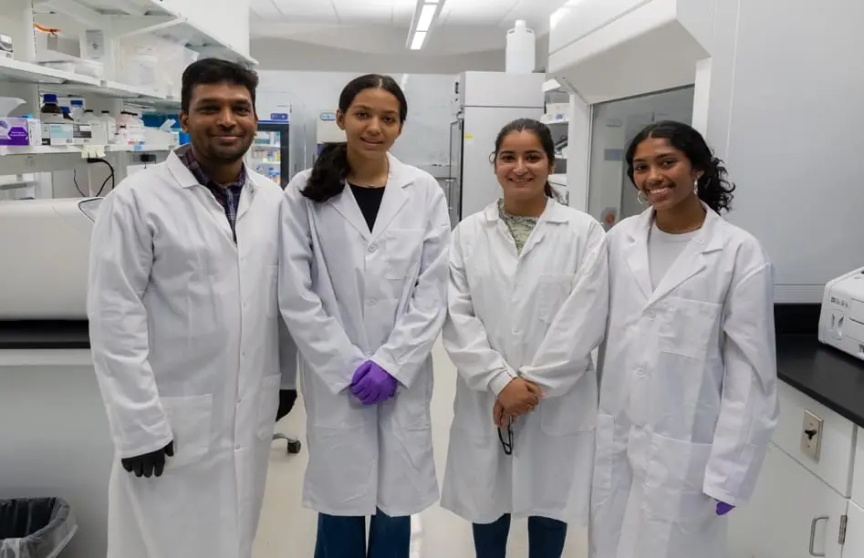 Four lab members in lab coats standing in the laboratory